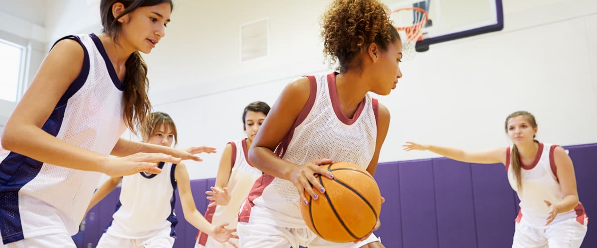 Teen girls playing basketball on an indoor court