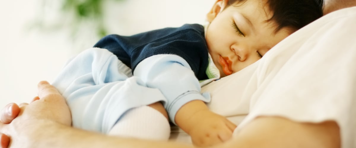 An infant asleep on his father's chest